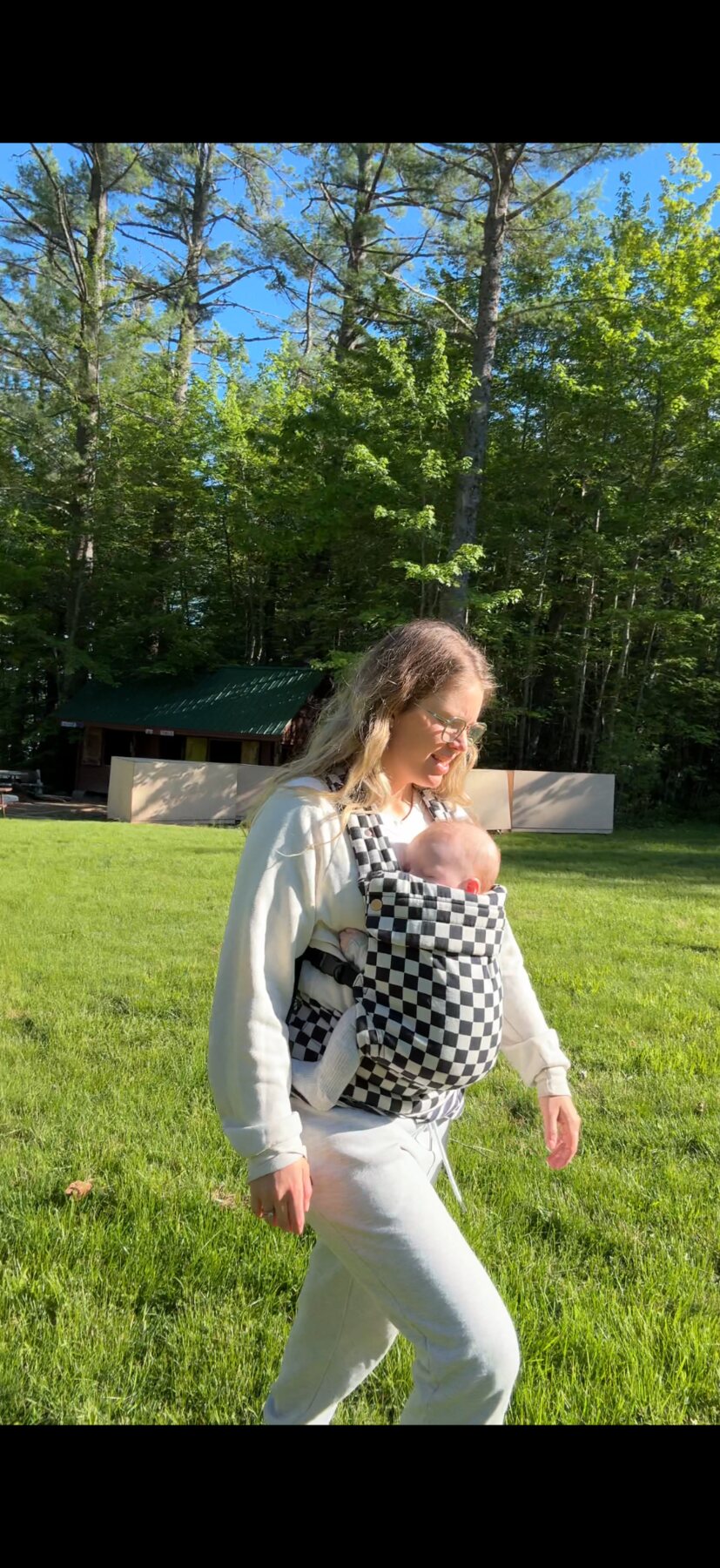 Robyn walking outside with her baby facing inward in a carrier